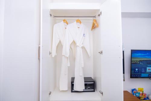a closet with white clothes on hangers and a tv at Le Dream Hotel near Vigan in Anomang Mayor