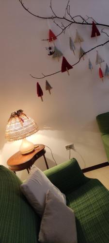 a living room with a green couch and a branch with birds on the wall at A casa di zia Maly in Palena