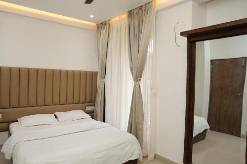 a bedroom with a large bed and a window at Belle-Vue Holiday Homes - 1BHK Apartments in Panchgani