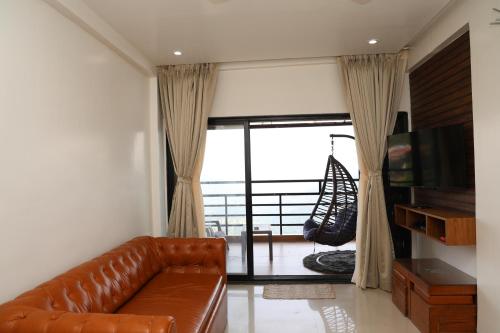 a living room with a leather couch and a television at Belle-Vue Holiday Homes - 1BHK Apartments in Panchgani