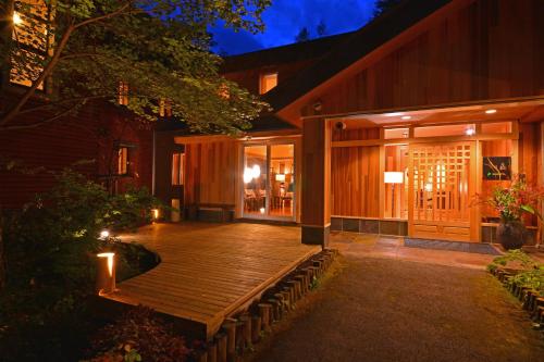 a wooden deck in front of a building at night at 奥日光湯元温泉ゆの森 in Nikko