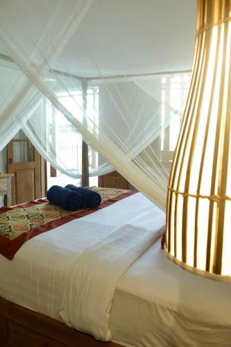 a white canopy bed with blue pillows on it at Melati bali villa in Canggu