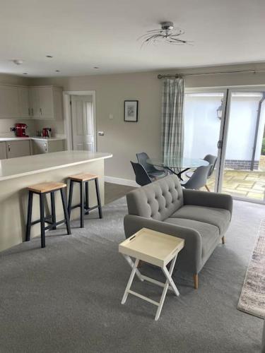 a living room with a couch and tables and a kitchen at Spacious, Modern Bungalow in Newton Regis