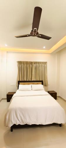 a bedroom with a white bed with a ceiling fan at Belle-Vue Holiday Homes - 1BHK Apartments in Panchgani