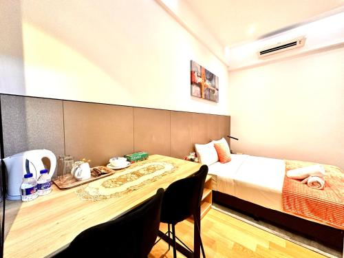 a room with a bed and a desk with a table at The Luxe Colony Klcc By NTR Resources in Kuala Lumpur