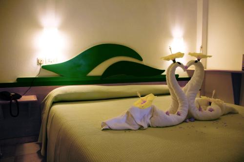 two stuffed swans sitting on top of a bed at Hotel Villaggio Cala Di Volpe in Capo Vaticano