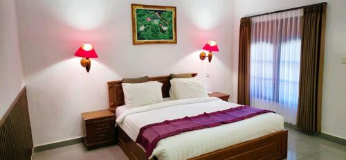 a bedroom with a bed with two lamps on the wall at Stana Puri Gopa Hotel in Sanur