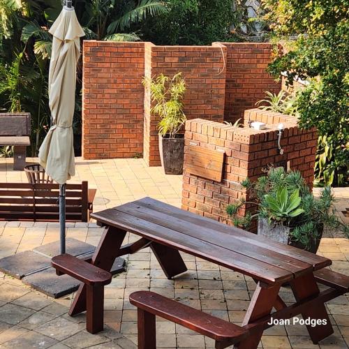 a wooden picnic table and an umbrella on a patio at Bon A Vie Self-catering and b&b Gonubie Full Solar Power, no load shedding! in Gonubie