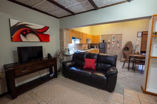 a living room with a leather couch and a television at Waterfalls Boutique Hotel in Pretoria