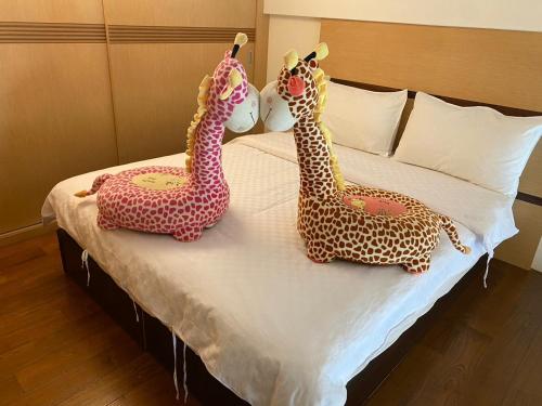 two toy giraffes are sitting on a bed at 石焦溫泉民宿 in Jiaoxi