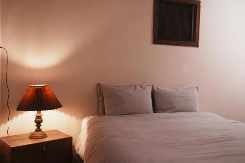 a bedroom with a bed with a lamp on a night stand at 牧嶼 Nomads' Isle in Jinhu