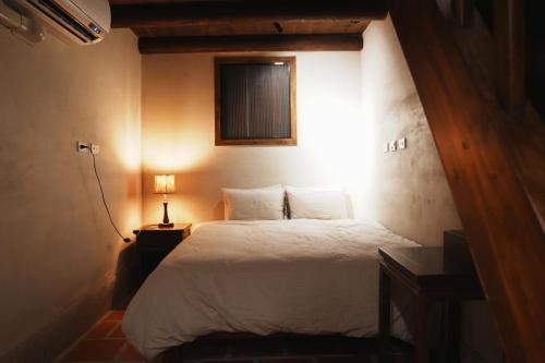 a bedroom with a white bed with a window at 牧嶼 Nomads' Isle in Jinhu