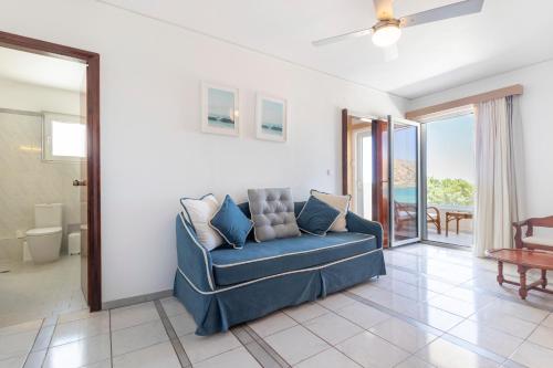 a living room with a blue couch and a balcony at Pal Beach in Palaiochora