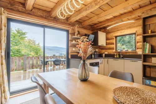 une cuisine et une salle à manger avec une table et une grande fenêtre dans l'établissement Chalet Chataigne - Magnifique vue montagne, à Cornimont