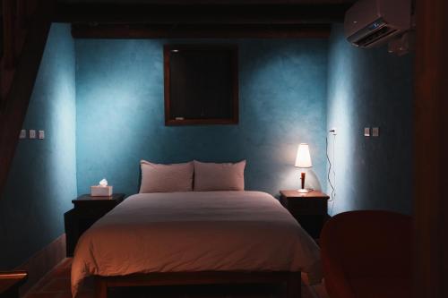 a bedroom with a large bed with a blue wall at 牧嶼 Nomads' Isle in Jinhu