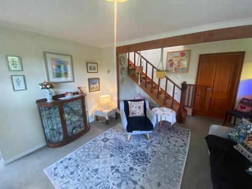 a living room with a staircase and a chair at Cherry Tree Cottage in Lawrence