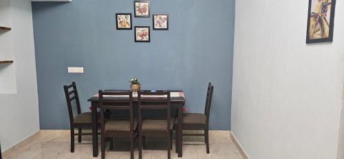 a dining room table with chairs and a blue wall at SHIs Aathira 2bhk Heart of Coimbatore in Coimbatore