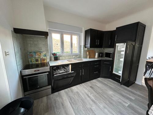 - une cuisine avec des placards noirs et un évier dans l'établissement Gite Bonheur du Pré-Salé, à Pontorson