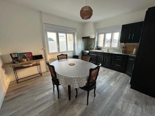 une cuisine avec une table et des chaises dans une cuisine dans l'établissement Gite Bonheur du Pré-Salé, à Pontorson