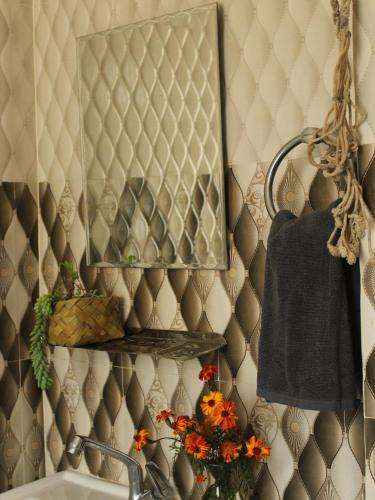 a mirror on a wall above a sink in a bathroom at La Casa by Cosmic Kriya in Bīr