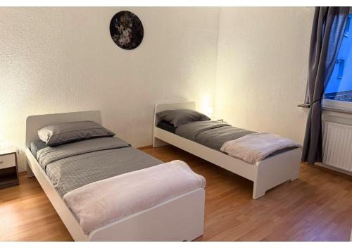 two beds in a room with a clock on the wall at Zentrale Wohnung mit Küche & 4 Betten in Oelde Stay Nest in Oelde