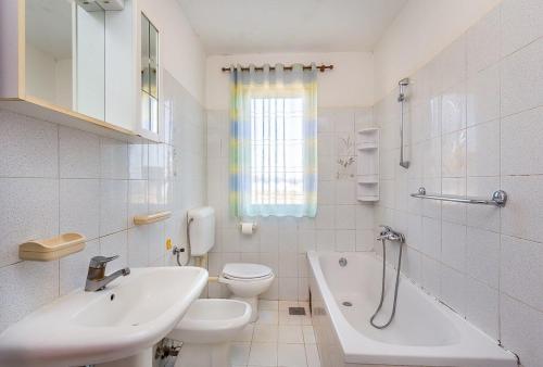 a white bathroom with a sink and a toilet and a tub at Apartment Sissano in Ližnjan