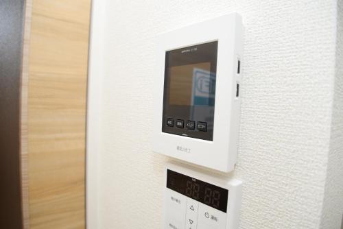 a microwave oven with a clock on the wall at NYHotel 1 新宿2階建て4室1バスルーム1シャワー2トイレ in Tokyo