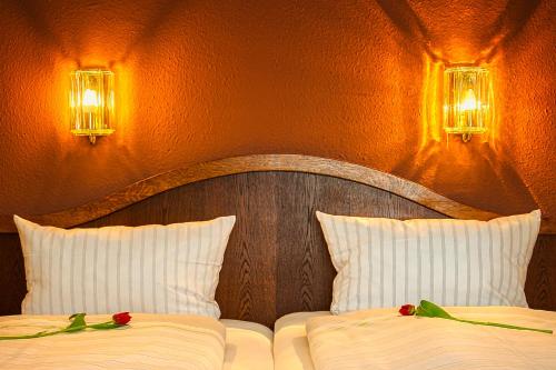 two beds in a bedroom with two roses on them at Reichels Parkhotel in Bad Windsheim