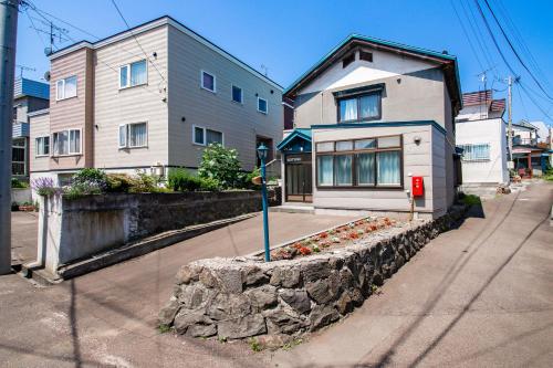 a house with a stone wall next to a street at KOTONE in Otaru