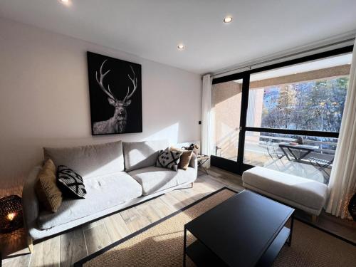 un salon avec un canapé et une grande fenêtre dans l'établissement Résidence Jardin Alpin Benoite - Appartement · Chaleureux · Accès direct aux pistes · Vue montagne MAE-3771, à La Salle Les Alpes
