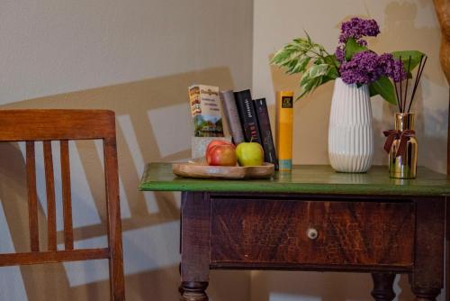 a table with a vase of flowers and apples and a vase of books at Landpension Birnthaler in Kallmünz