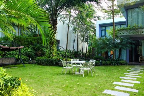 a yard with a table and chairs and palm trees at Flamigo Dai Lai Resort - Villa Chủ Tự Doanh in Ngọc Quang