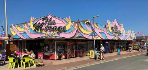 a store on a street with people sitting outside of it at 107 Headwards Retreat in Hemsby