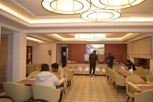 a group of people sitting at tables in a restaurant at Hotel The Haven - Centrally Heated and Air Conditioned in Kargil