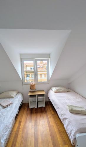 two beds in a room with a table and two windows at Somo Playa Vistas in Somo