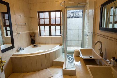 a bathroom with a tub and a shower and a sink at Waterfalls Boutique Hotel in Pretoria