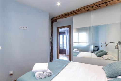 a bedroom with a bed and a mirror with towels at POLITXE Bermeo in Bermeo