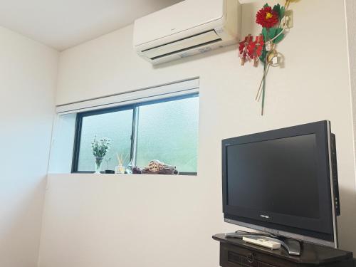 a flat screen tv in a room with a window at 熊野の恵みハウス in Hagi