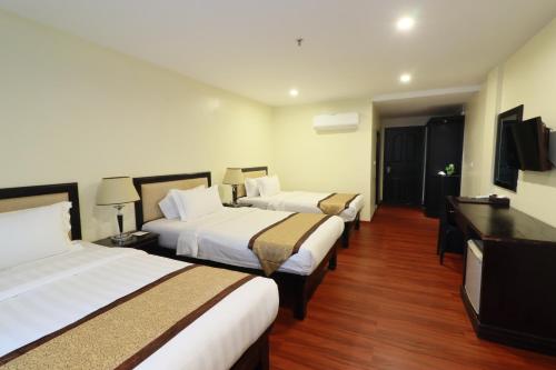 a hotel room with three beds and a flat screen tv at Mahasakor Inn in Phnom Penh