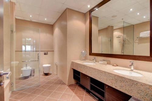 a bathroom with two sinks and a toilet and a mirror at Luxe Getaways Royal Amwaj Palm Jumeirah Resort Apartment Holiday Home in Dubai