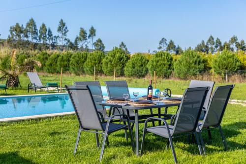 a table and chairs in the grass next to a pool at Casa Sol - Private Pool with a Large Garden in Mouchinha