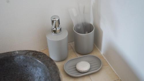 a bathroom with a toilet with a sink and a trash can at Summer of Surf Canggu in Canggu