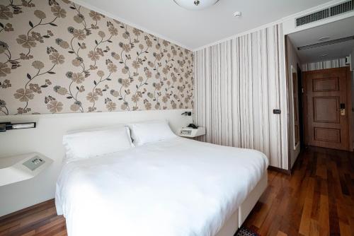 a bedroom with a white bed and a floral wallpaper at Phi Hotel Principe in Cuneo