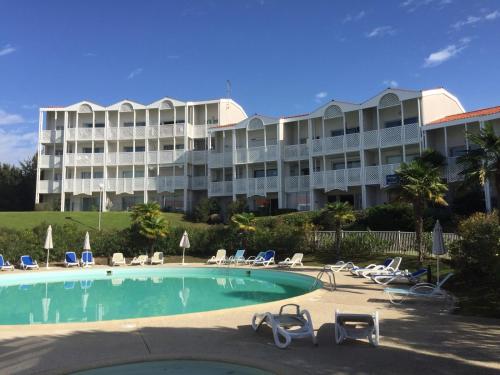 un grand immeuble avec une piscine et des chaises dans l'établissement ALIENOR VUE MER 2 à 4 PERSONNES, à Fouras