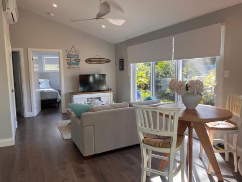 a living room with a couch and a table at Palm Cottage Avalon Beach in Avalon