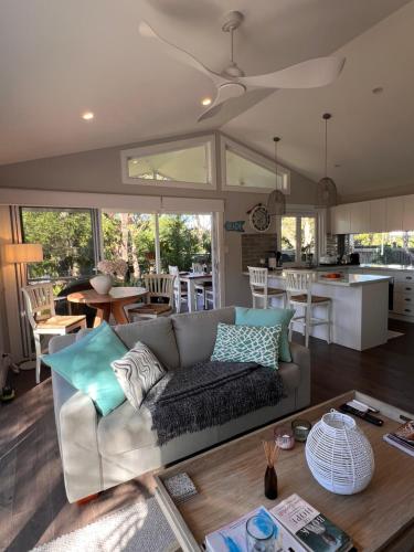 a living room with a couch and a kitchen at Palm Cottage Avalon Beach in Avalon