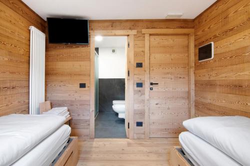 a room with wooden walls and a bedroom with beds at Agriturismo Montespluga in Madesimo