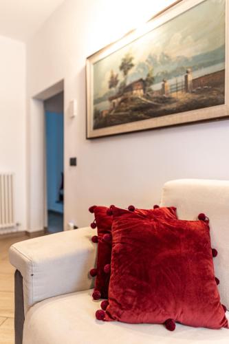 a red pillow on a white couch with a painting on the wall at Agriturismo Why Farm in Marano Ticino