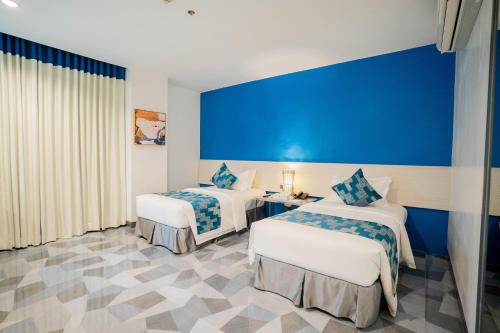 a hotel room with two beds and a blue wall at Stacia Hotel in Cebu City