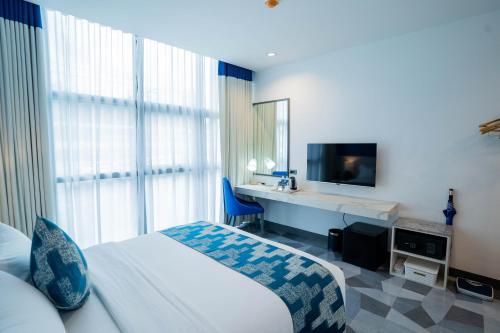a hotel room with a bed and a desk with a television at Stacia Hotel in Cebu City